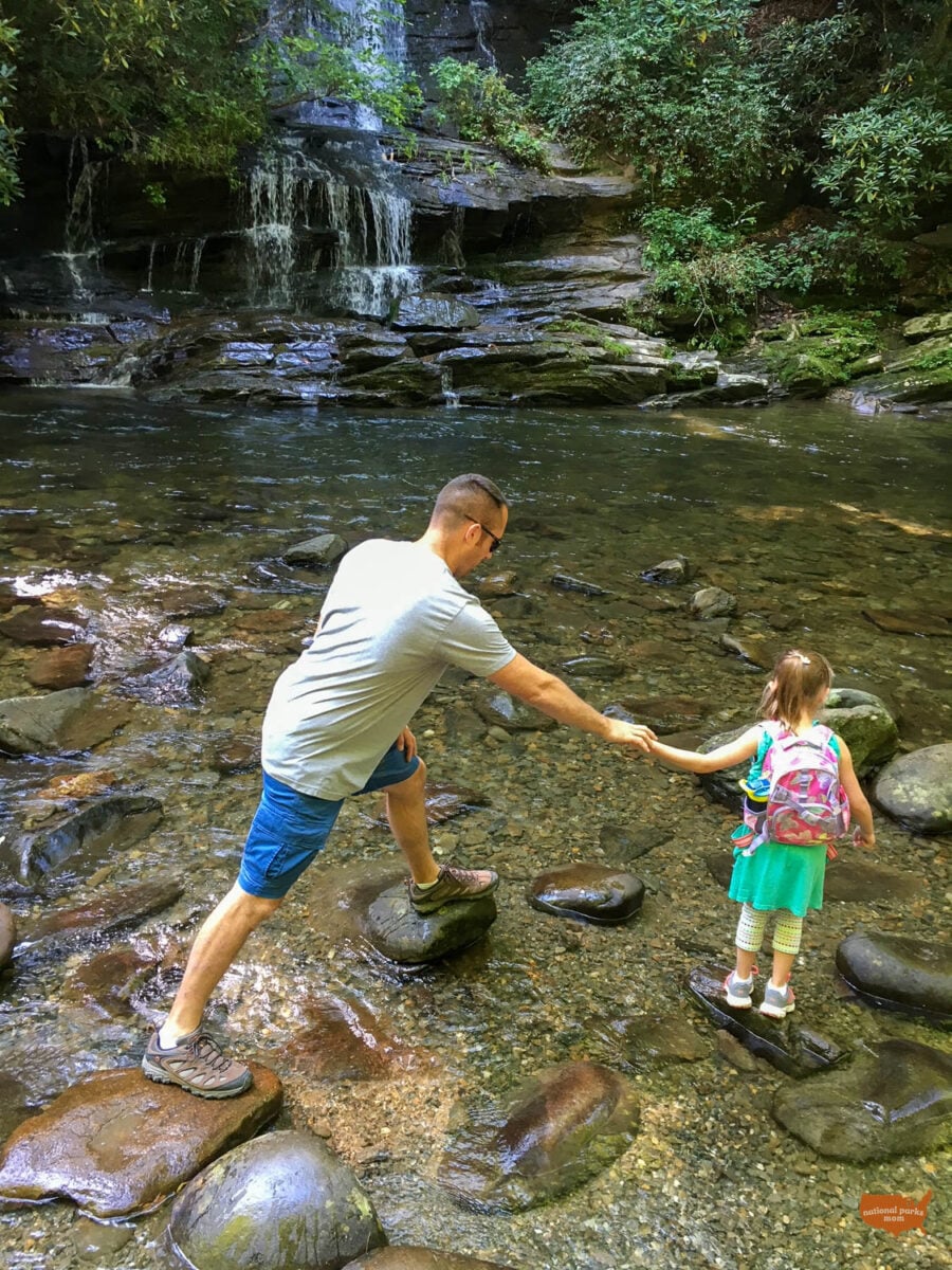 daughter and dad wading in one of the creeks near a waterfall in Great Smoky Mountains National Park