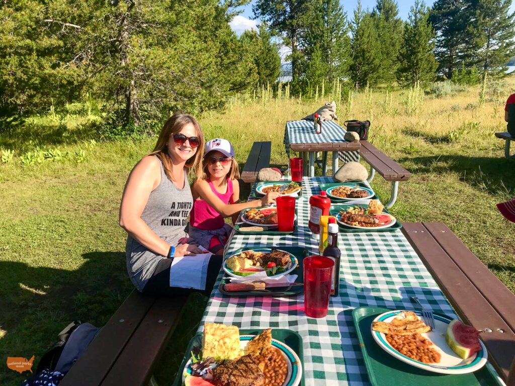 family enjoying dinner outside on the shore of Jackson Lake during a scenic dinner cruise in Grand Teton National Park, WY