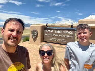 three people in front of NPS Entrance sign for Great Sand Dunes National Park in Colorado